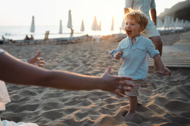 Eine junge Familie mit einem Kleinkind, das sich im Sommerurlaub am Strand amüsiert. - HPIF23950