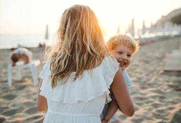 A young mother with a toddler boy having fun on beach on summer holiday. - HPIF23951