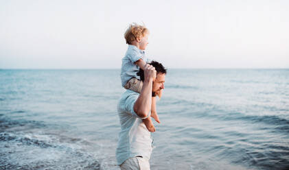 Älterer Vater mit einem kleinen Jungen, der im Sommerurlaub am Strand spazieren geht und Spaß hat. - HPIF23957