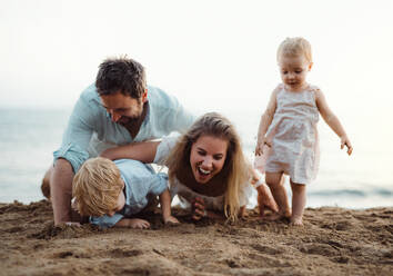 Eine junge Familie mit Kleinkindern spielt im Sommerurlaub am Strand mit Sand. - HPIF23968