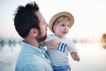 Ein reifer Vater hält ein Kleinkind am Strand im Sommerurlaub. - HPIF24003