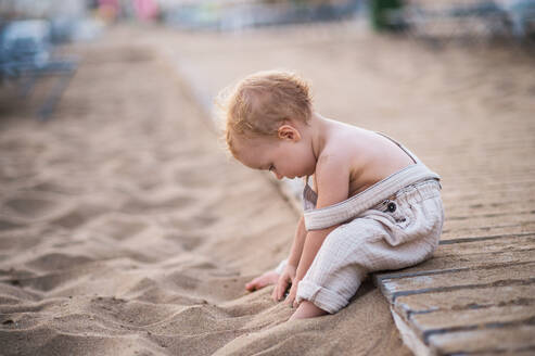 Ein süßes kleines Kleinkind Mädchen sitzt am Strand im Sommerurlaub, spielen. kopieren Raum. - HPIF24009