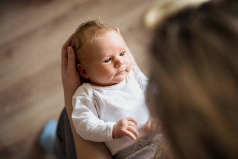 Ein Mittelteil einer nicht erkennbaren Mutter, die ein neugeborenes Baby zu Hause im Arm hält. - HPIF24062