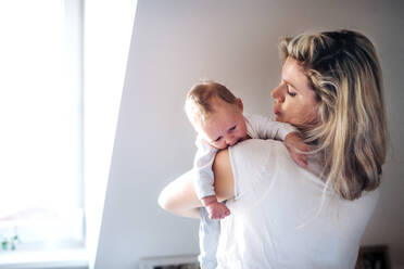 A beautiful young mother holding a newborn baby at home. Copy space. - HPIF24064