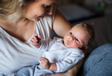 Eine schöne junge Mutter, die ihr neugeborenes Baby zu Hause im Arm hält. - HPIF24066