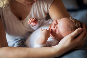 Ein Mittelteil einer nicht erkennbaren Mutter, die ein schlafendes Neugeborenes zu Hause hält. - HPIF24067