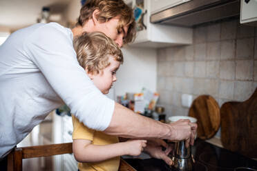 Ein junger Vater mit einem kleinen Sohn verbringt seine Zeit in der Küche seines Hauses. - HPIF24092