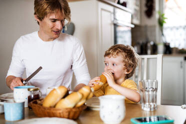 Ein junger Vater mit einem kleinen Sohn frühstückt zu Hause. - HPIF24099