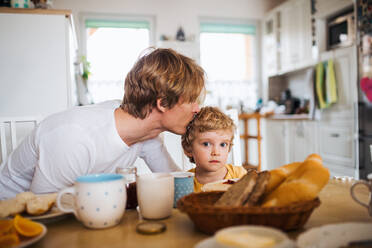 Ein junger Vater mit einem kleinen Sohn frühstückt zu Hause. - HPIF24101