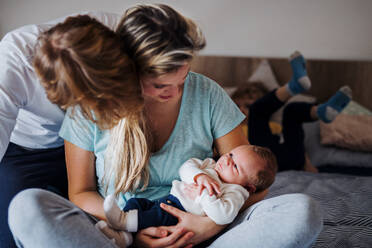 Junge Eltern mit einem neugeborenen Baby und einem kleinen Kleinkind zu Hause. - HPIF24138