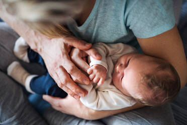 Ein Mittelteil von jungen Eltern mit einem neugeborenen Baby zu Hause, Ansicht von oben. - HPIF24139