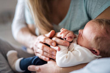 Ein Mittelteil einer nicht erkennbaren Mutter, die ein schlafendes Neugeborenes zu Hause hält. - HPIF24140