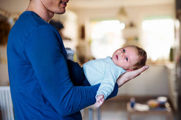 Ein junger Vater, der sein neugeborenes Baby zu Hause im Arm hält. - HPIF24145