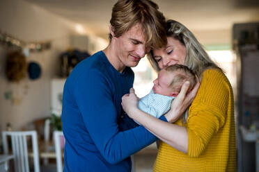 Beautiful young parents holding a newborn baby at home. - HPIF24147