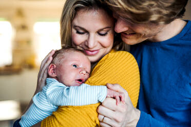 Schöne junge Eltern, die ein neugeborenes Baby zu Hause im Arm halten. - HPIF24154
