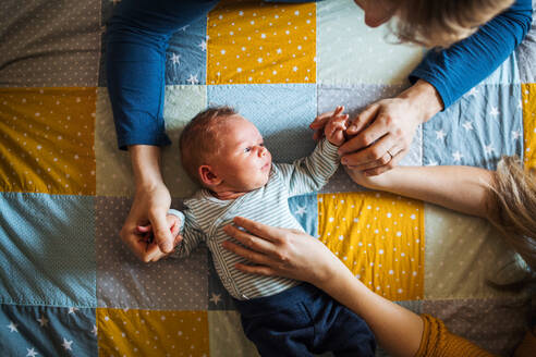 Draufsicht auf ein neugeborenes Baby, das zu Hause auf einer Steppdecke im Bett liegt. - HPIF24157