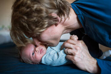 Nahaufnahme eines jungen Vaters, der sein neugeborenes Baby zu Hause im Arm hält und es küsst. - HPIF24160