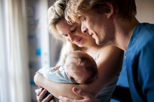 Schöne junge Eltern, die ein neugeborenes Baby zu Hause im Arm halten. - HPIF24166