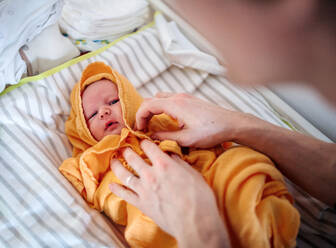 Unbekannter Vater trocknet ein Neugeborenes nach einem Bad zu Hause mit einem Handtuch ab. - HPIF24169
