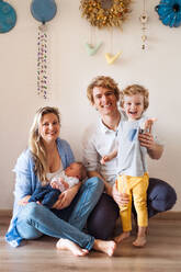 Porträt von jungen Eltern mit einem neugeborenen Baby und einem kleinen Kleinkind zu Hause. - HPIF24180