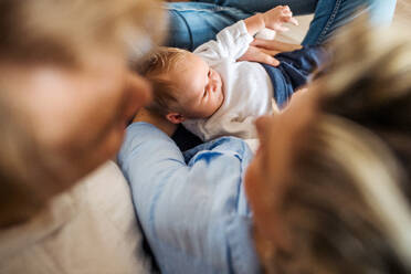 Ein Blick von oben auf unerkennbare junge Eltern mit einem neugeborenen Baby zu Hause. - HPIF24182