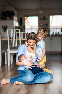 Eine schöne junge Mutter mit einem neugeborenen Baby und seinem kleinen Bruder zu Hause. - HPIF24189