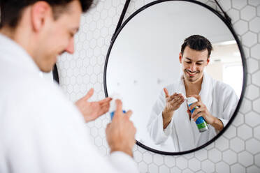 Ein junger Mann rasiert sich morgens im Badezimmer, eine tägliche Routine. - HPIF24239