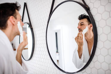 A young man shaving in the bathroom in the morning, a daily routine. - HPIF24240