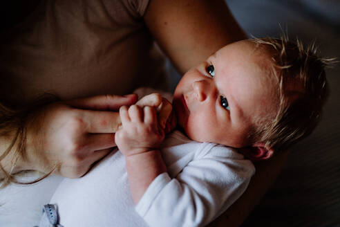 Ein Mittelteil einer nicht erkennbaren Mutter, die ein neugeborenes Baby zu Hause im Arm hält. - HPIF24306
