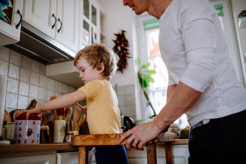 Ein nicht erkennbarer Vater mit einem kleinen Sohn verbringt seine Zeit in einer Küche zu Hause. - HPIF24309