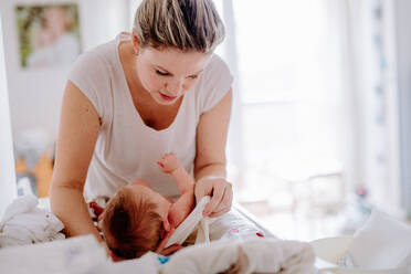 Vorderansicht einer schönen jungen Mutter, die sich zu Hause um ein neugeborenes Baby kümmert. - HPIF24310