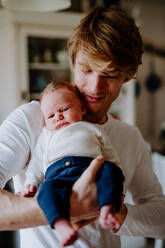 Ein junger Vater hält ein neugeborenes Baby zu Hause, Vorderansicht. - HPIF24313