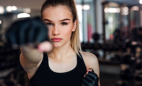 Vorderansicht eines jungen Mädchens oder einer Frau mit Handschuhen, die in einem Fitnessstudio trainieren. - HPIF24348