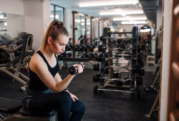 Ein junges Mädchen oder eine junge Frau mit Hanteln, die in einem Fitnessstudio trainieren. - HPIF24353