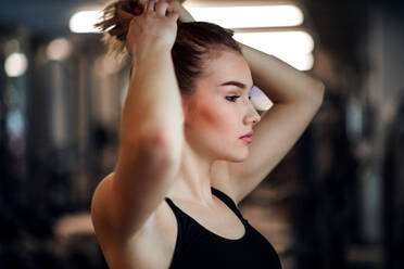 A portrait of a beautiful young girl or woman standing in a gym. - HPIF24354