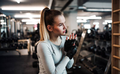 Junges Mädchen oder Frau mit fingerlosen Handschuhen, die in einem Fitnessstudio trainieren. - HPIF24357