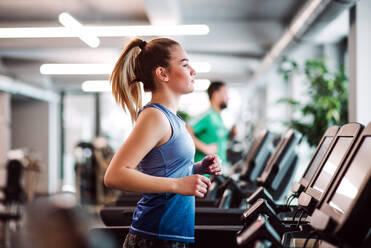 Ein Porträt eines schönen jungen Mädchens oder einer Frau beim Cardio-Training in einem Fitnessstudio. - HPIF24371