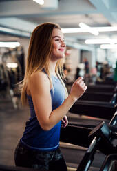 Ein Porträt eines schönen jungen Mädchens oder einer Frau beim Cardio-Training in einem Fitnessstudio. - HPIF24374