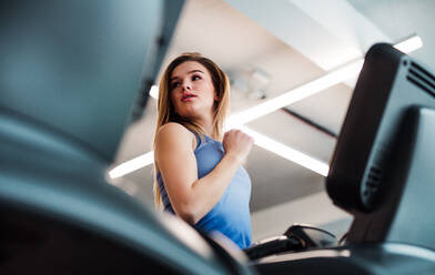 Ein Porträt eines schönen jungen Mädchens oder einer Frau beim Cardio-Training in einem Fitnessstudio. - HPIF24376