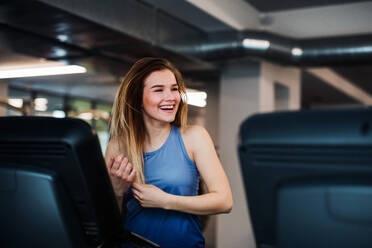 A portrait of a beautiful young girl or woman doing cardio workout in a gym. - HPIF24379