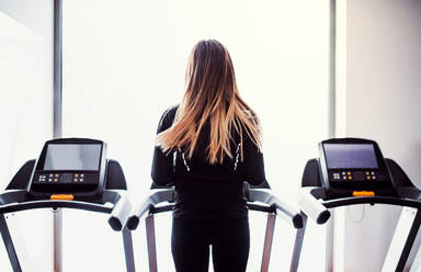 A rear view of a beautiful young girl or woman doing cardio workout in a gym. - HPIF24404