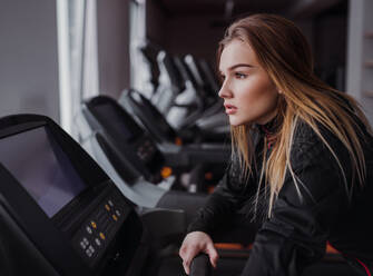 Eine Seitenansicht eines schönen jungen Mädchens oder einer Frau beim Cardio-Training in einem Fitnessstudio. - HPIF24405