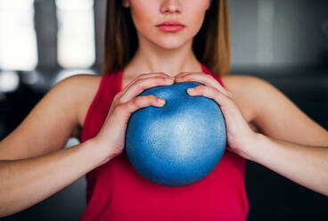 A midsection of beautiful young girl or woman doing exercise with a ball in a gym. - HPIF24417