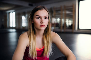 A portrait of young sad girl or woman sitting in a gym. Copy space. - HPIF24421