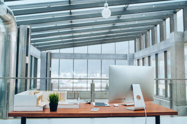 Ein Interieur von einem Schreibtisch mit Computer und Modell eines Hauses in modernen geräumigen Büro. - HPIF24532