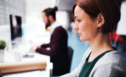 Zwei junge Geschäftsleute arbeiten in einem Büro und benutzen einen Computer. - HPIF24625