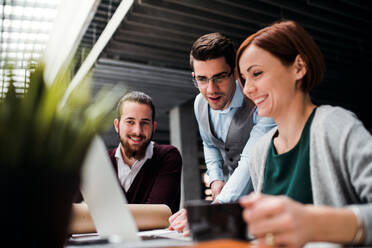 A group of young businesspeople working together in office, talking. - HPIF24627