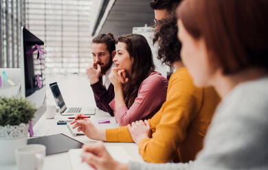 A group of young businesspeople working together in office, talking. - HPIF24634