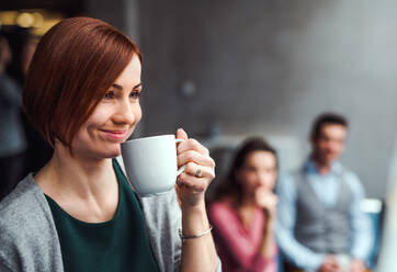 Eine Gruppe junger Geschäftsleute sitzt mit Kaffee im Büro. - HPIF24640