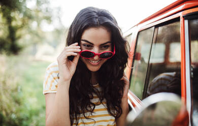 Ein Mädchen mit Sonnenbrille schaut in den Spiegel auf einem Roadtrip durch die Landschaft. - HPIF24713